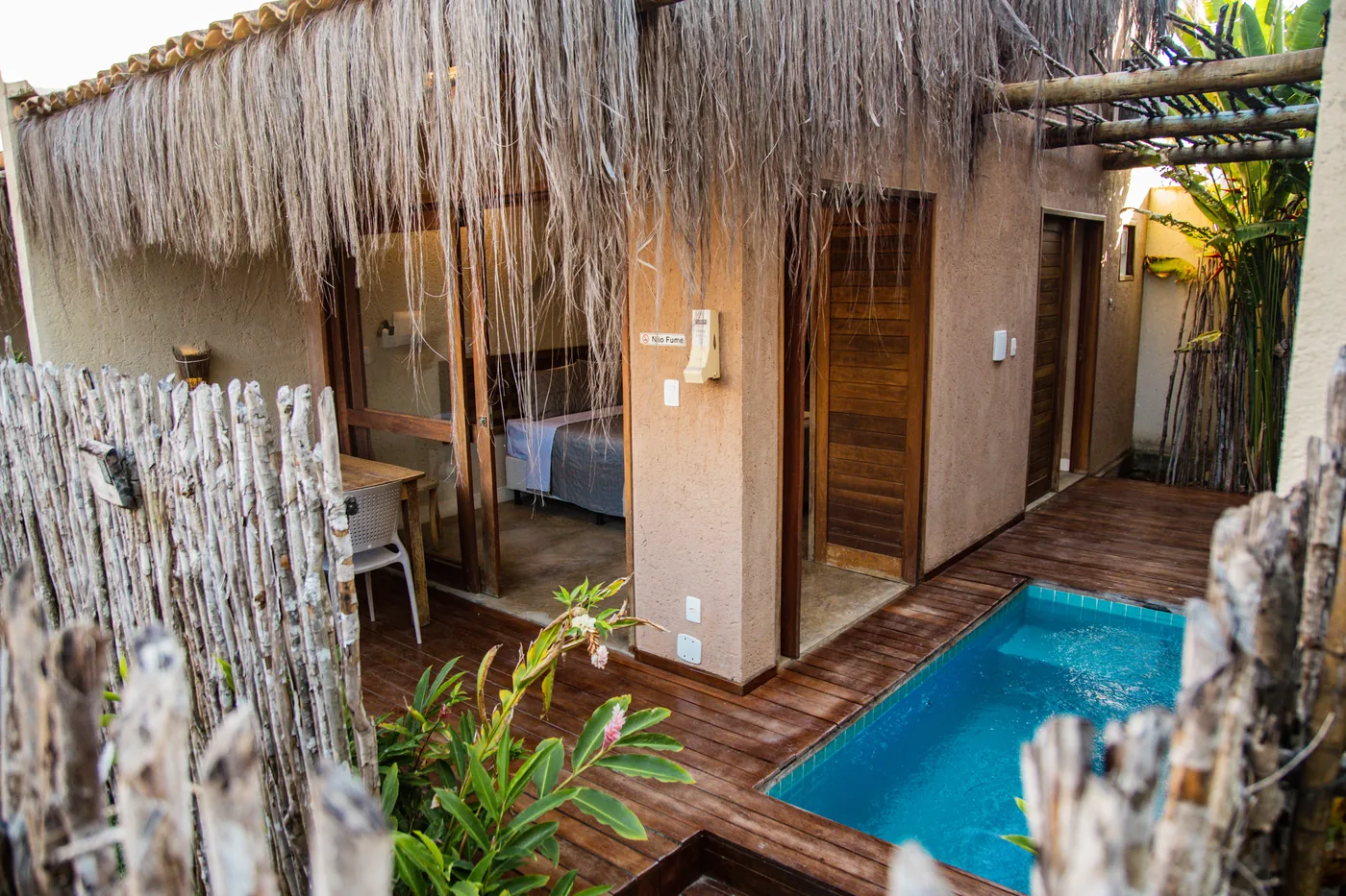Piscina privativa azul junto ao deck de madeira e à entrada de uma suíte do Naim.