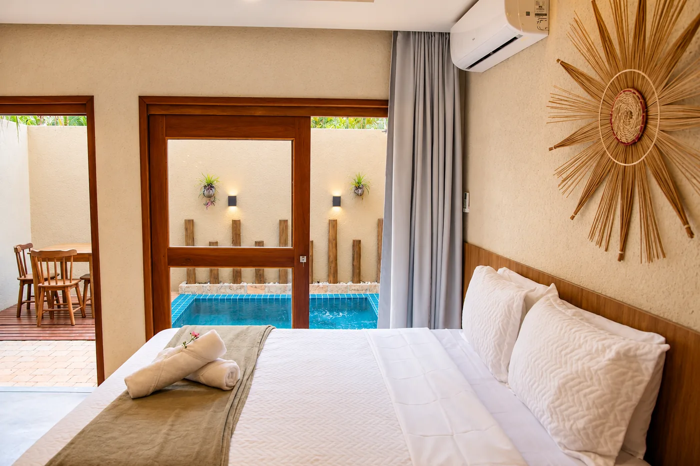 Suíte do Naim com cama de casal, decoração em fibras naturais e piscina privativa junto à porta de vidro.